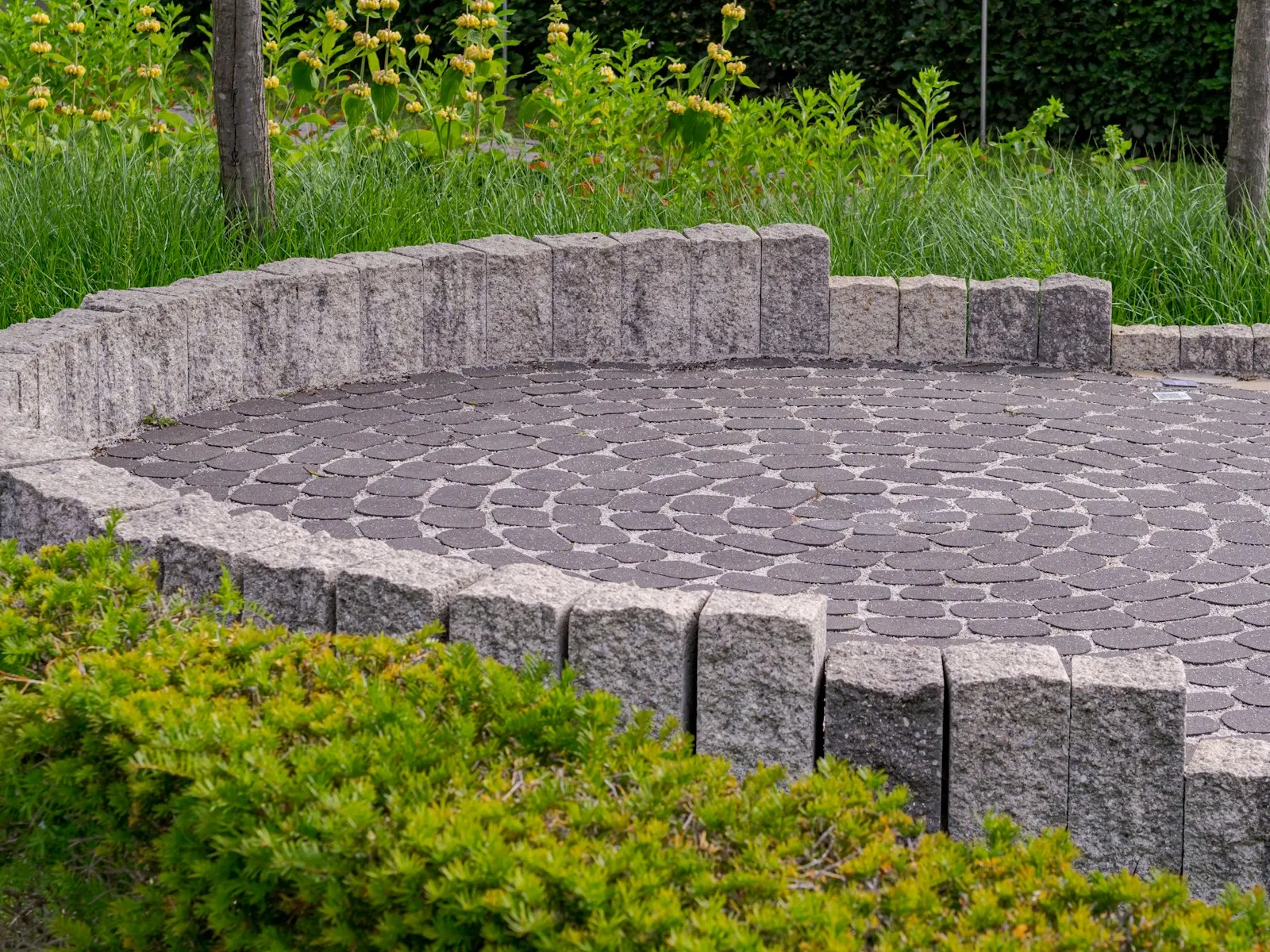 Terasă circulară din piatră naturală cu zid scund